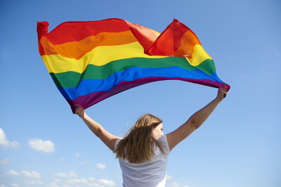 Una mujer sostiene la bandera del orgullo. Imagen: Freepik