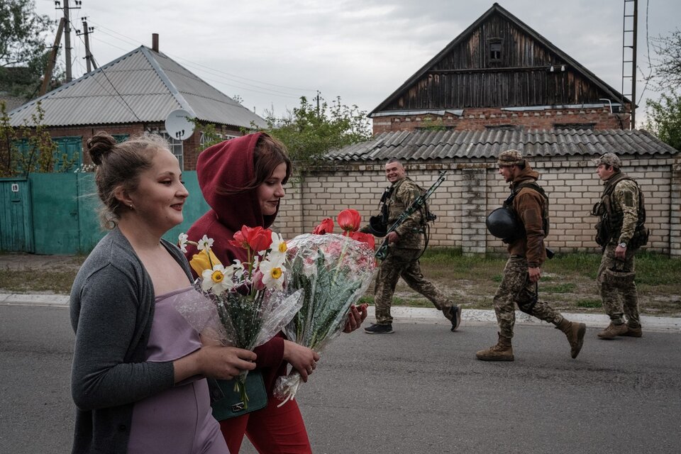 Mujeres con flores y soldados armados se cruzan en Raihodorok, Ucrania.  (Fuente: AFP)