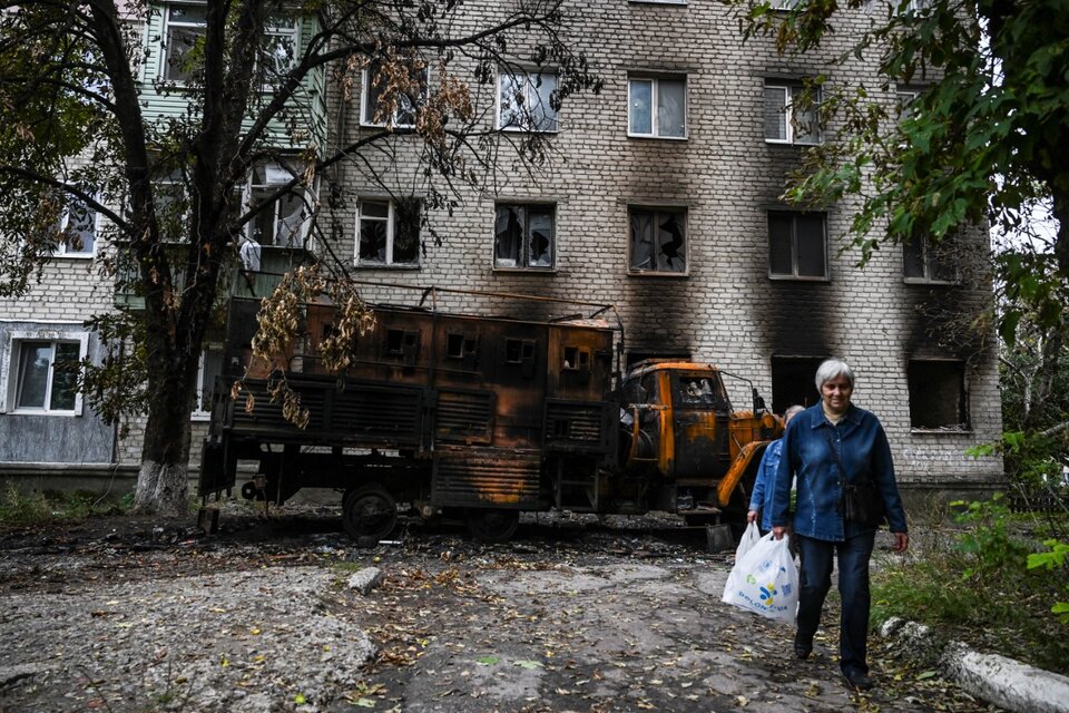 Dos mujeres caminan frente a una casa bombardeada en Balakliya, región de Kharkiv. (Fuente: AFP)
