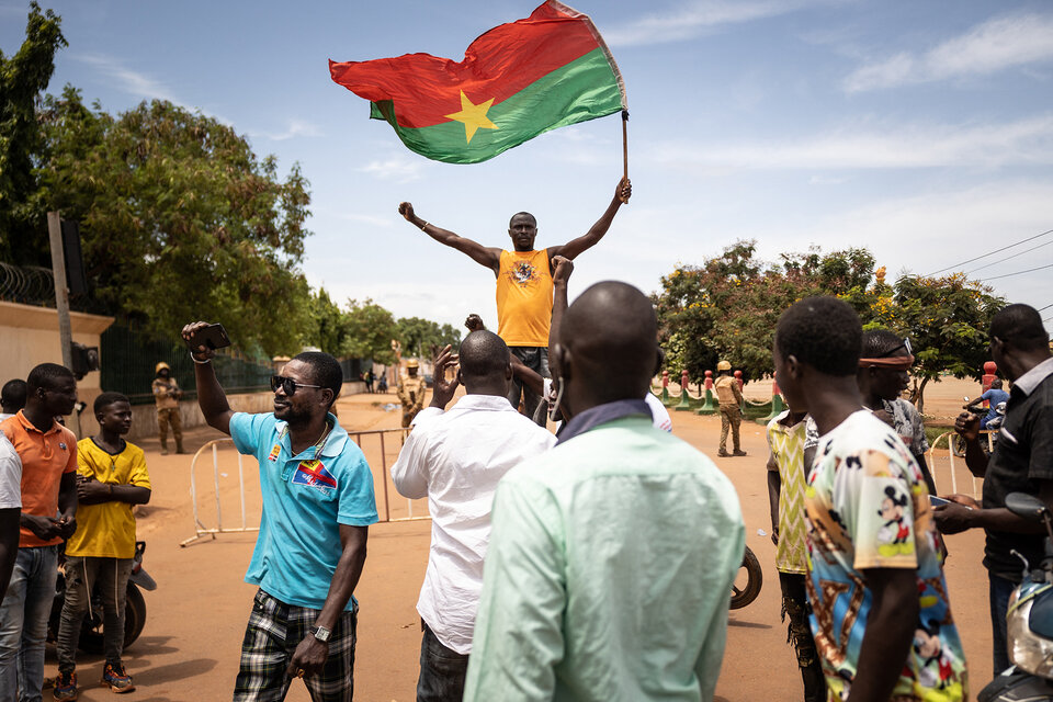 Un hombre flamea una bandera de Burkina Faso mientras militares ocupan posiciones en Ouagadougou horas antes del golpe de Estado. (Fuente: AFP)