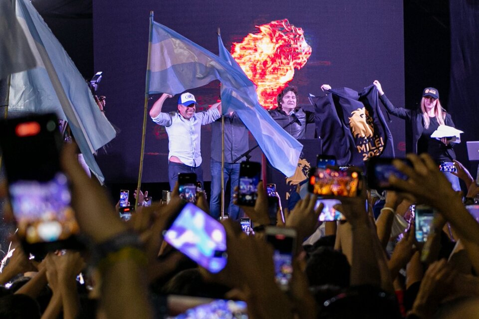 Frente a las banderas argentina, Ricardo Bussi y Javier Milei saludan en el escenario con los brazos en alto. (Fuente: Atilio Orellana)