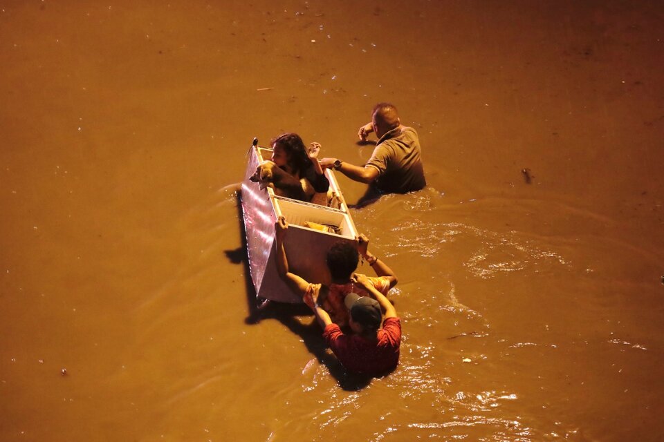 Los rescatistas usan una heladera como canoa para salvaguardar a unos niños. (Fuente: EFE)