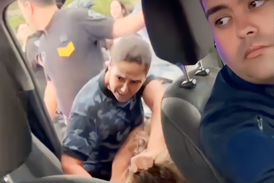 La agente policial entrando de los pelos a la joven al móvil.