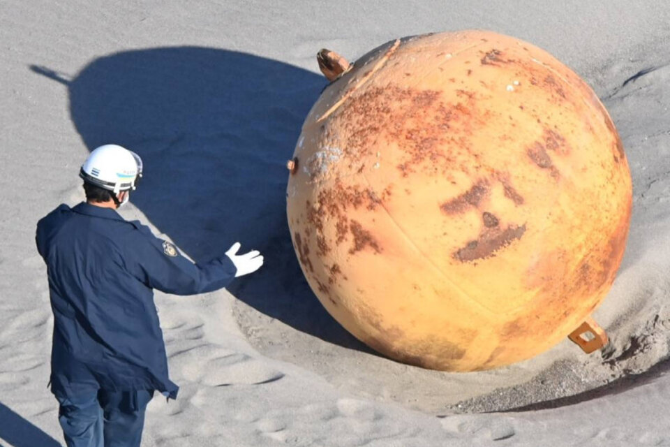 Dos agentes del escuadrón antibombas analizaron la esfera de metal encontrada en la playa japonesa de Enshuhama. (Foto: @lauraparquokka)