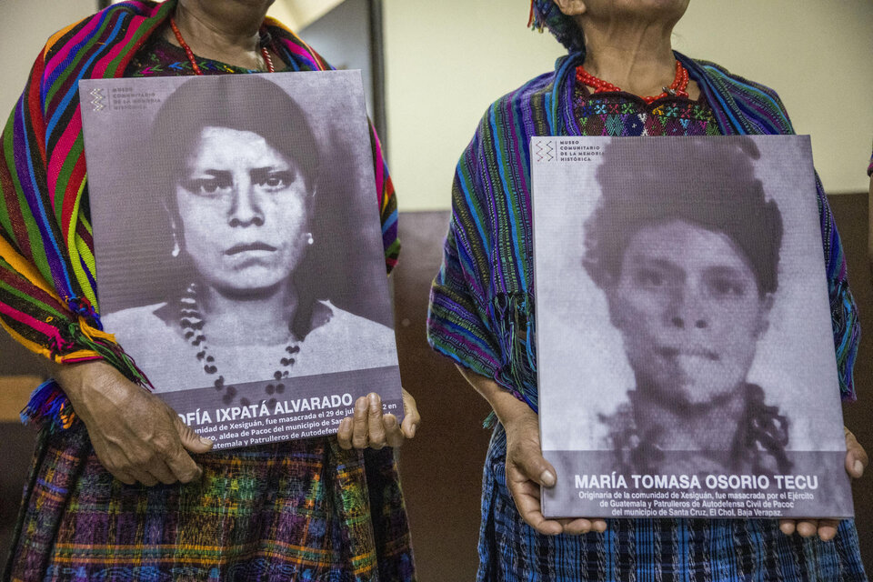 Paulina Ixpatá y Máxima Garcia, sobrevivientes de la masacre del Rancho Bejuco posan con el retrato de sus familiares masacradas. (Fuente: EFE)