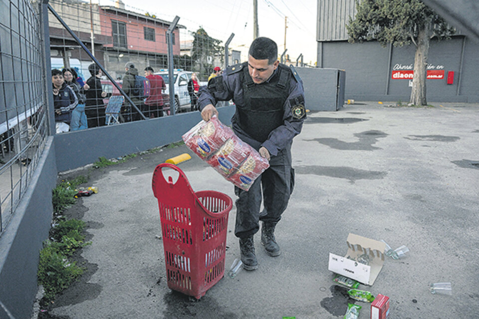 Un efectivo de la bonaerense recupera mercadería robada en José C. Paz. (Fuente: AFP)