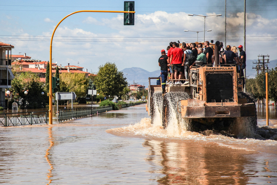 Un grupo de personas son evacuadas en una excavadora Caterpillar en una zona inundada en Larisa, en el centro de Grecia (Fuente: AFP)