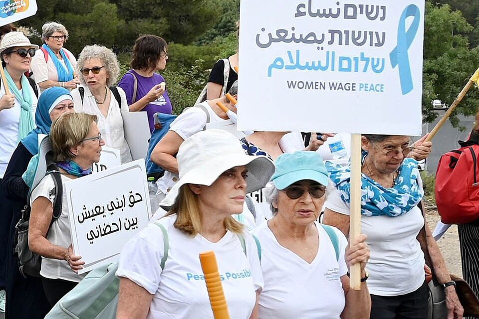 Vivian, gorro con visera celeste, lleva el cartel :Mujeres que luchan por la paz. 