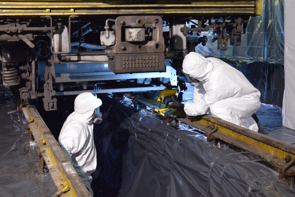 Trabajadores con trajes aislantes realizando tareas en las formaciones contaminadas de marca Mitsubishi de la línea B.