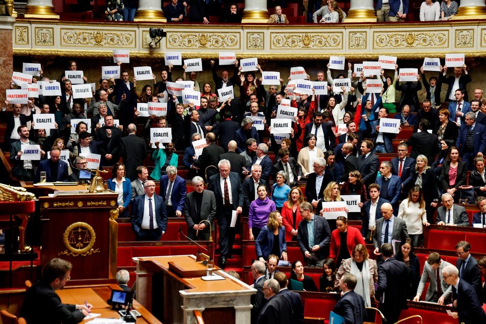 Los parlamentarios de la coalición de izquierda NUPES sostienen carteles con el lema nacional de Francia, tras la aprobación de la ley.  (Fuente: AFP)