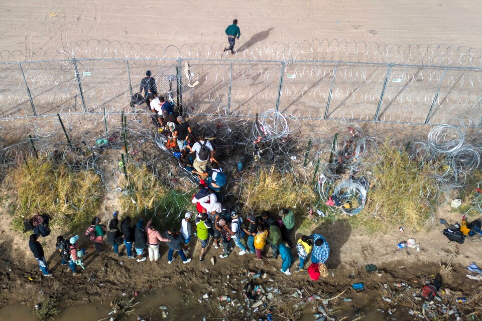 Inmigrantes cruzan la frontera por un agujero en el alambrado en El Paso, Texas. (Fuente: AFP)