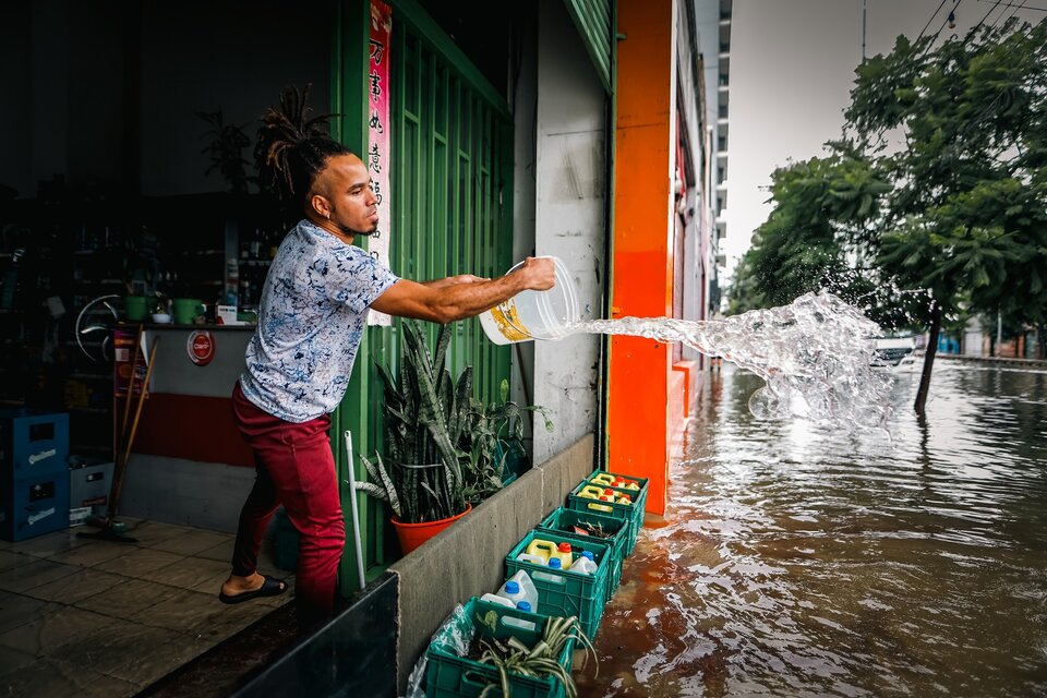 Un hombre evacua el agua de su negocio frente a una calle inundada por la lluvia este miércoles, en Buenos Aires. (Fuente: EFE)