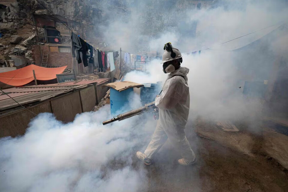 Un integrante de una brigada de salud fumiga una calle para evitar la propagación del dengue en el distrito de San Juan de Lurigancho, en Lima, el pasado 11 de mayo. 