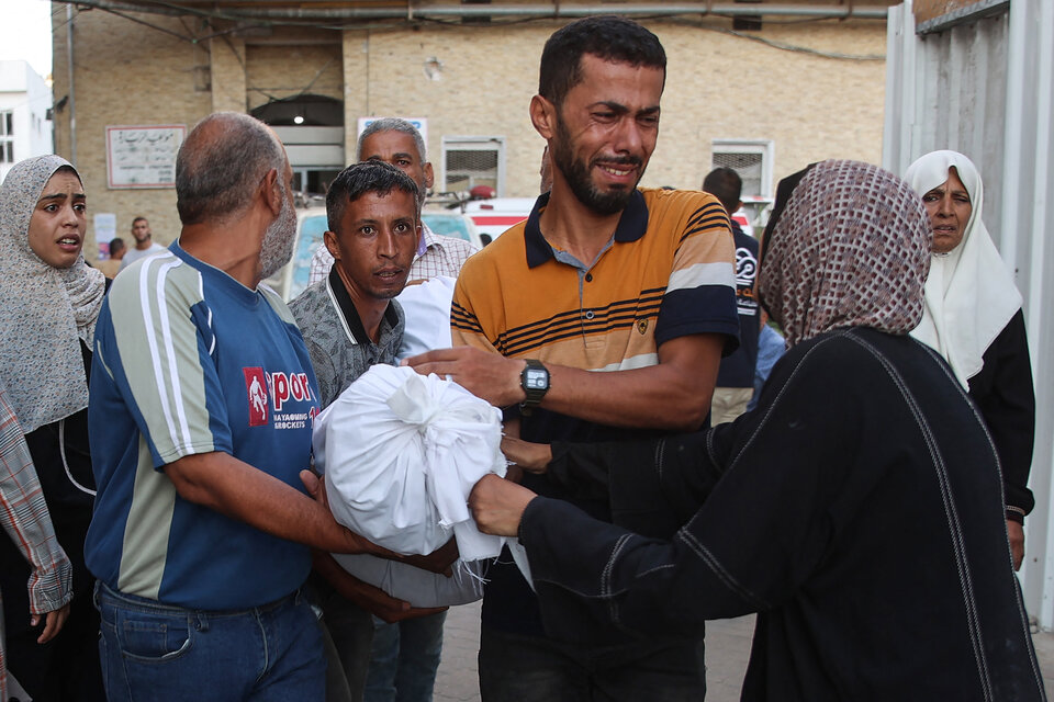 Palestinos llevan a un hospital de Gaza el cuerpo de un familiar muerto en la escuela. (Fuente: AFP)