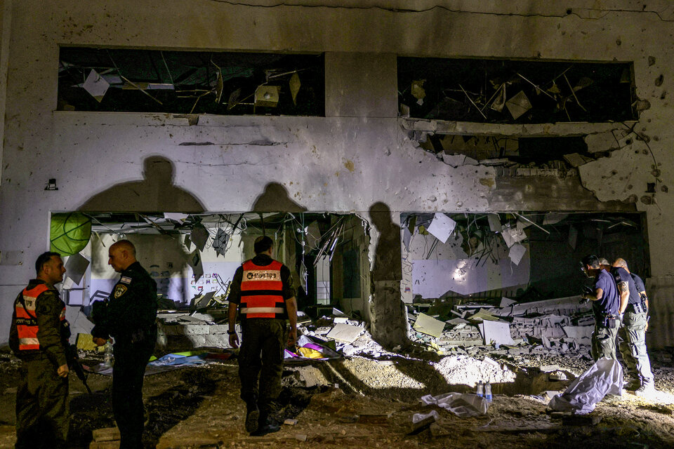 Fuerzas de seguridad israelíes inspeccionan un crater que dejó un misil iraní en la ciudad de Gedera. (Fuente: AFP)