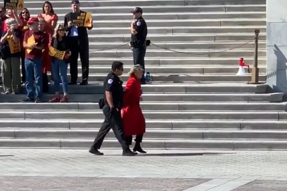 Fonda, llevada por un oficial, con la smanos atadas, durante la protesta en Washington.  (Fuente: Captura de pantalla)