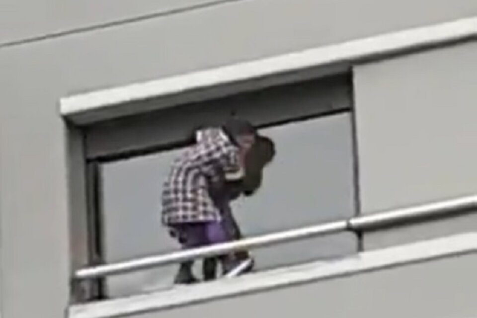 La mujer que limpia la ventana, del lado de afuera, en un sexto piso.  (Fuente: Captura de pantalla)