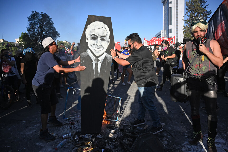 Unos manifestantes protestan usando la imagen de Piñera.