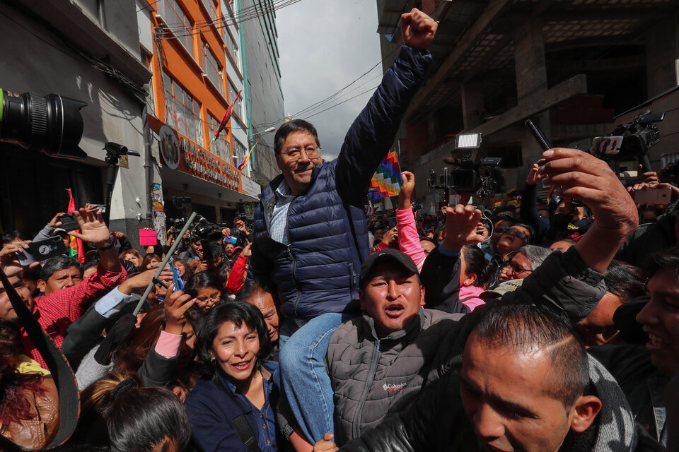 1. Luis Arce llevado en andas al llegar a La Paz para anotarse como candidato por el MAS. 2. Evo levanta la mano de Arce tras su proclamación en Buenos Aires. (AFP)  (Fuente: AFP)