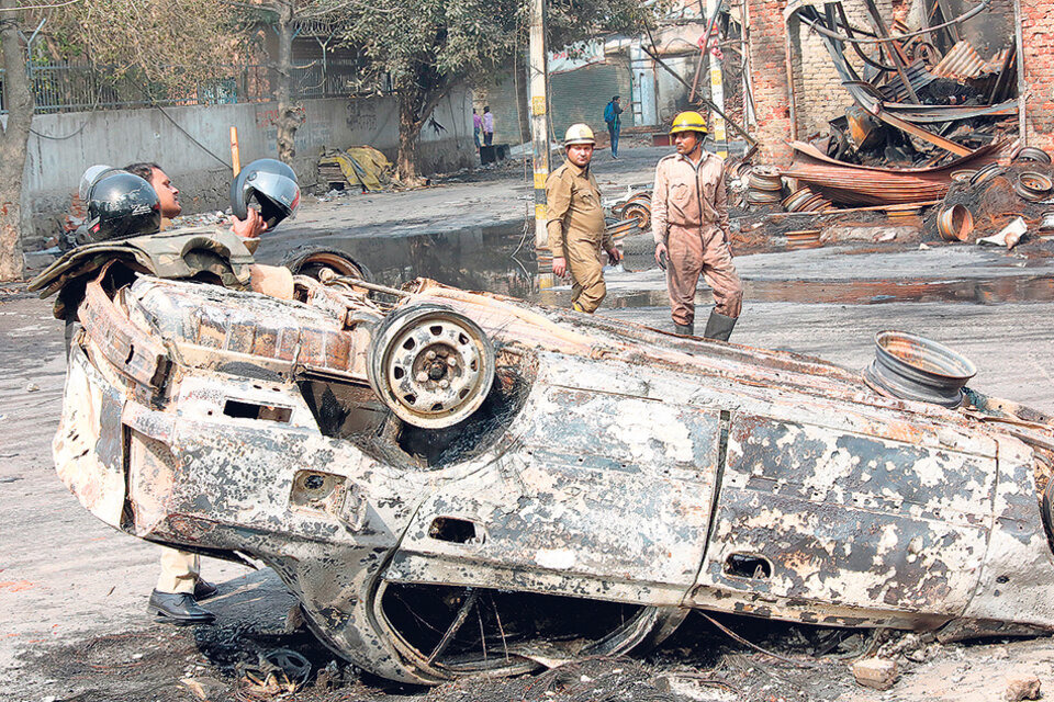 Bomberos apagan un auto incendiado en nueva Delhi en medio de los enfrentamientos. (Fuente: AFP)