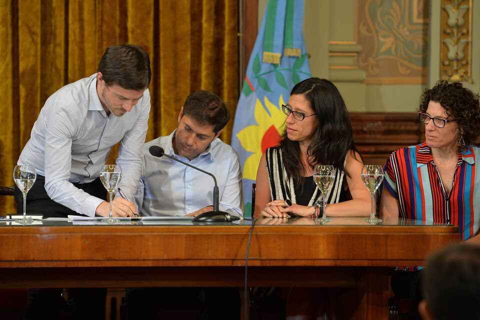 Costa firma ante la mirada de Kicillof y Paula Español. (Fuente: NA)