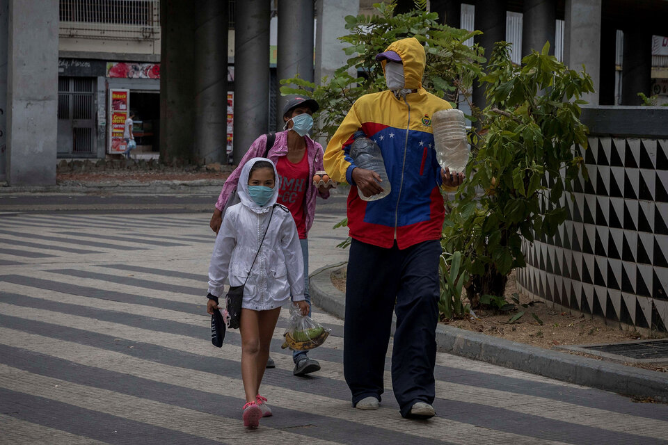 Una familia camina por las calles de Caracas cargando agua y fruta. (Fuente: EFE)