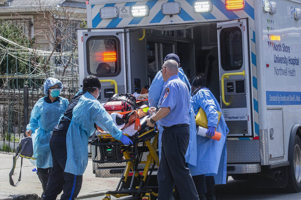 Enfermeros cargan a un enfermo de coronavirus en Queen, Nueva York.  (Fuente: AFP)