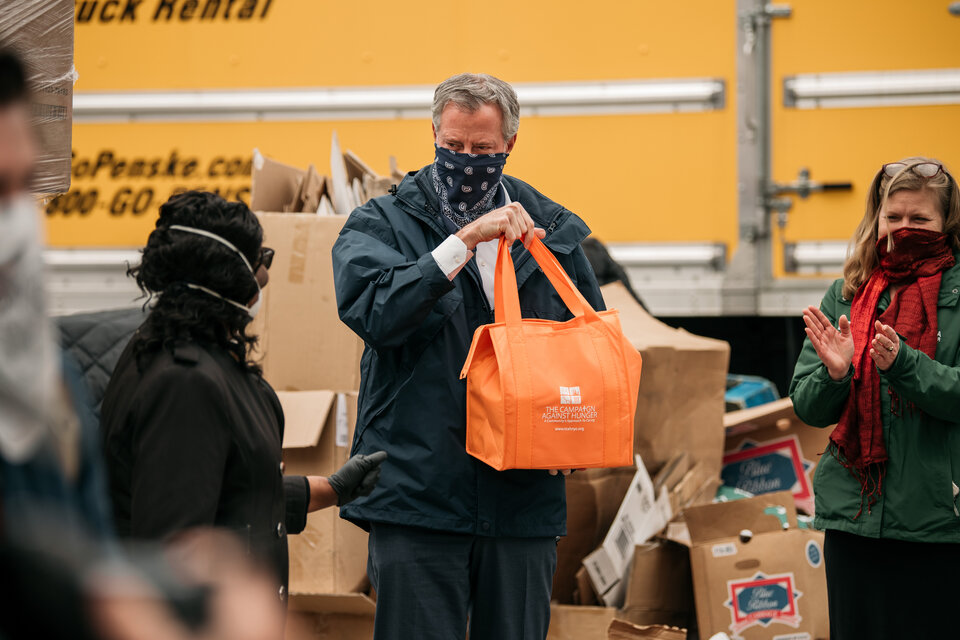 De Blasio sostiene una bolsa de comida en un refugio para personas sin techo de Brooklyn. (Fuente: AFP)