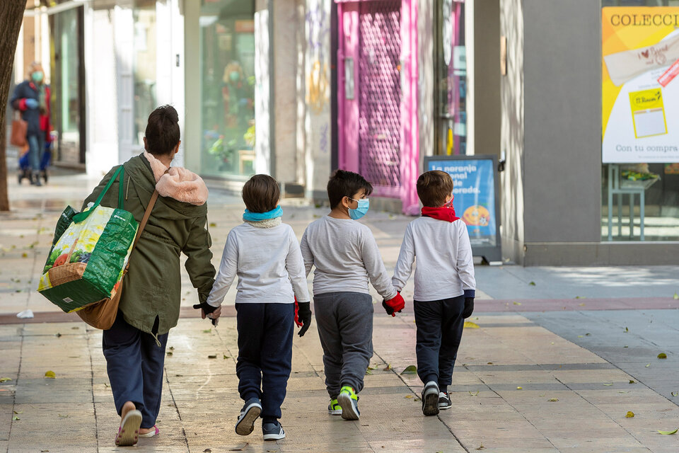 Una mujer y tres niños con guantes y barbijos caminan de la mano en Zargoza. (Fuente: EFE)
