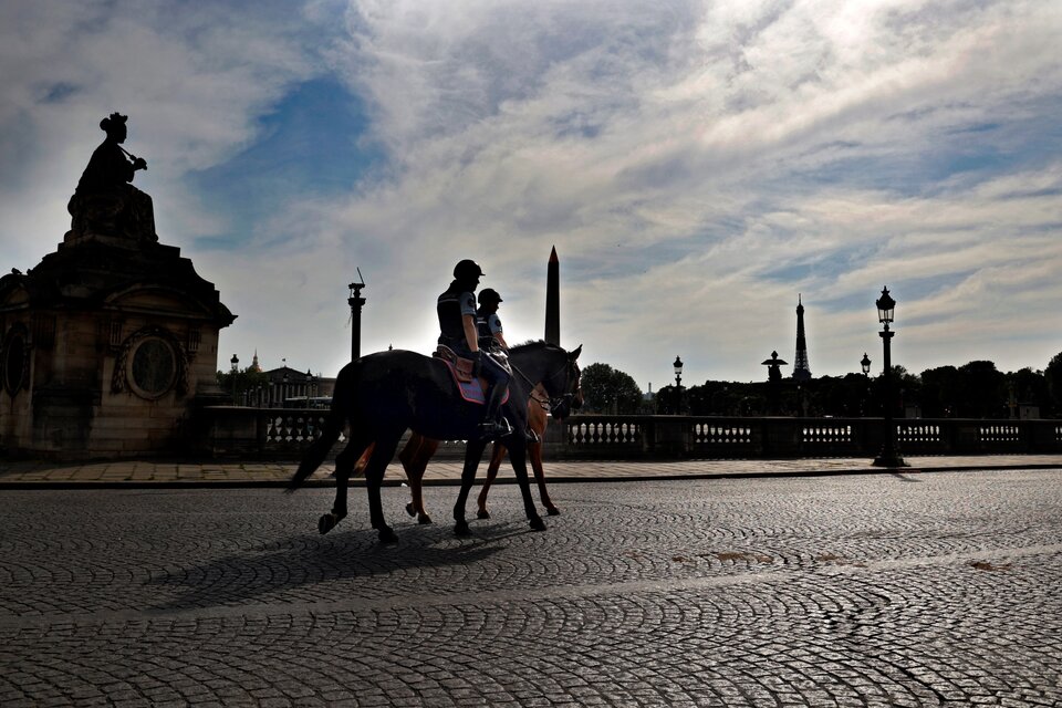 Dos policías montados patrullan las calles desiertas de París en plena cuarentena por el coronavirus.  (Fuente: AFP)
