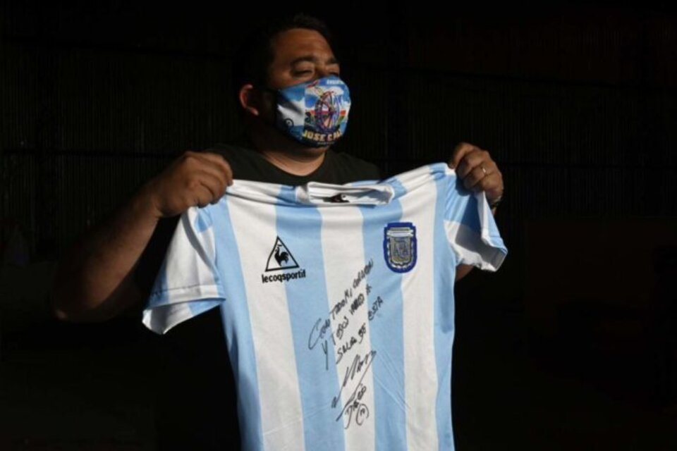Diego Maradona y la camiseta firmada que donó para juntar fondos. (Fuente: Twitter)