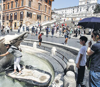 Los turistas se refrescan en la fuente Barcaccia, en la plaza España, en una Roma de calor agobiante. (Fuente: EFE) (Fuente: EFE) (Fuente: EFE)