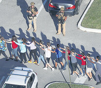 Un grupo de estudiantes evacúa la escuela secundaria de Parkland después de la masacre perpetrada por un ex alumno.