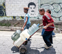 Un hombre empuja un carretilla con bidones cargados en un canal de aguas servidas en Caracas. (Fuente: AFP) (Fuente: AFP) (Fuente: AFP)