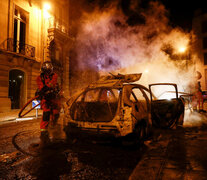 Un bombero apaga el incendio intencional de un automóvil. (Fuente: AFP) (Fuente: AFP) (Fuente: AFP)