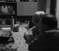 Una pareja mayor contempla con ternura una pantalla apoyada en la mesa del comedor. Del taller de fotografía de La Vigil. (Fuente: Gabriel Terrera) (Fuente: Gabriel Terrera) (Fuente: Gabriel Terrera)