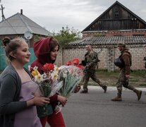 Mujeres con flores y soldados armados se cruzan en Raihodorok, Ucrania.  (Fuente: AFP) (Fuente: AFP) (Fuente: AFP)