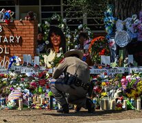 Un oficial de policía limpia el memorial improvisado en la escuela primaria Robb en Uvalde, Texas. (Fuente: AFP) (Fuente: AFP) (Fuente: AFP)