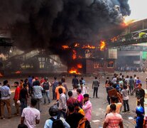 Manifestantes observan edificios gubernamentales incendiados en Daca (Fuente: AFP) (Fuente: AFP) (Fuente: AFP)