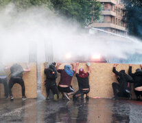 Resistiendo los chorros de los camiones hidrantes en las calles de Santiago. (Fuente: EFE) (Fuente: EFE) (Fuente: EFE)