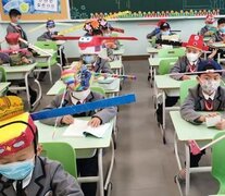 Una escuela de Zheijiang, China, donde los niños usan sombreros de cartón, con varillas a los costados para el distanciamiento.