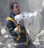 Un hombre cargaba a un niño rescatado de un bombardeo ayer en Hamouria, Guta Oriental. (Fuente: AFP)