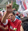 Rodeado por simpatizantes, Haddad hace la L de Lula con sus dedos durante su recorrida por Rocinha.