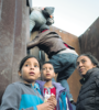 Niños de la caravana migrante trepan por una parte de la pared fronteriza. (Fuente: AFP)