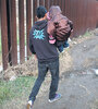 Un migrante con un niño en brazos camina en la frontera ente San Diego y Tijuana.