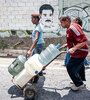 Un hombre empuja un carretilla con bidones cargados en un canal de aguas servidas en Caracas. (Fuente: AFP)