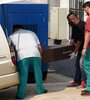 Empleados de la oficina forense cargan el cajón de una de las niñas en la morgue judicial. (Fuente: AFP)